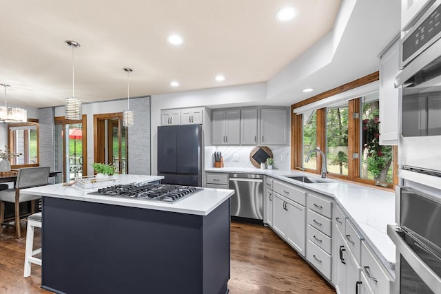 11280 Bluestem Ln, Eden Prairie, MN 55347 - kitchen featuring appliances with stainless steel finishes, a center island, decorative backsplash, dark wood finished floors, and decorative light fixtures