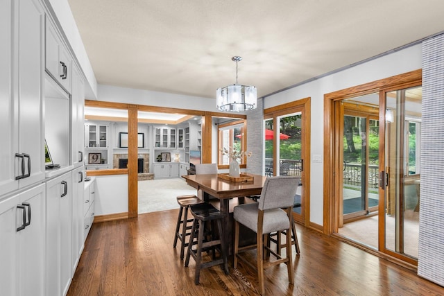 11280 Bluestem Ln, Eden Prairie, MN 55347 - dining space with a chandelier, a fireplace with raised hearth, and dark wood-type flooring