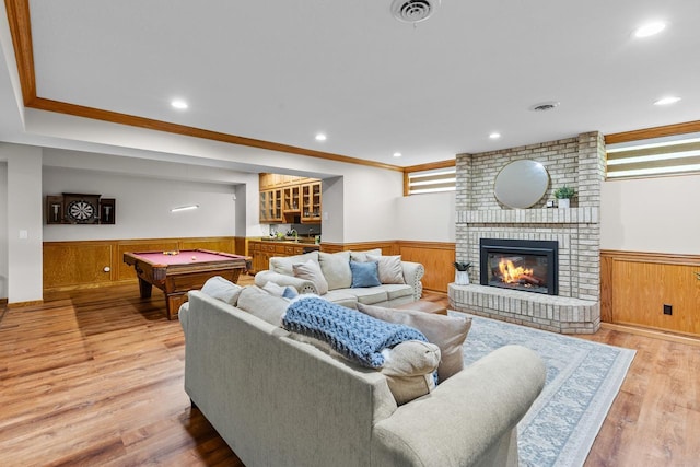 11280 Bluestem Ln, Eden Prairie, MN 55347 - living room featuring a wainscoted wall, pool table, a brick fireplace, ornamental molding, and light wood-style flooring