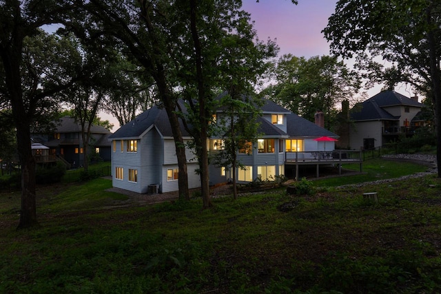 11280 Bluestem Ln, Eden Prairie, MN 55347 - back of property at dusk with a wooden deck, a lawn, and a chimney