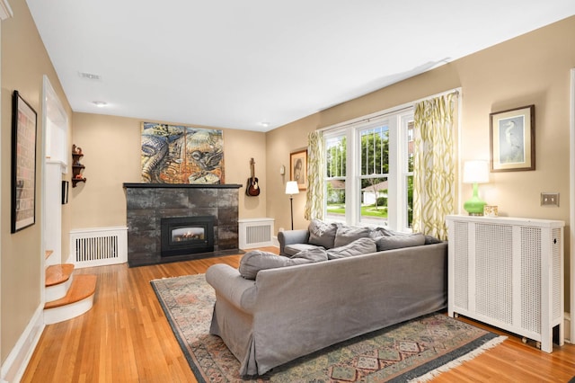 901 42nd St, Minneapolis, MN 55409 - living room featuring radiator, wood finished floors, and a tiled fireplace