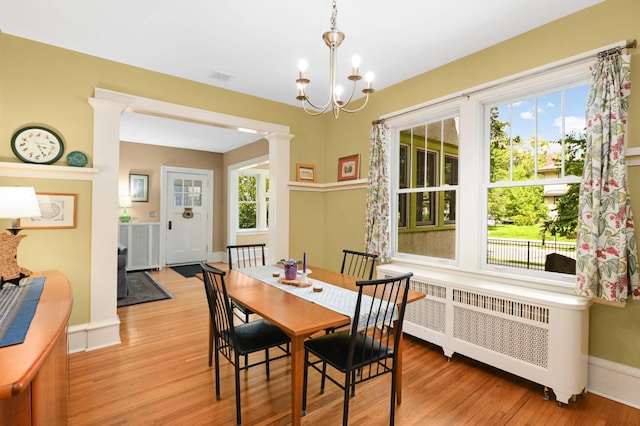 901 42nd St, Minneapolis, MN 55409 - dining space with radiator heating unit, light wood-style flooring, and a chandelier