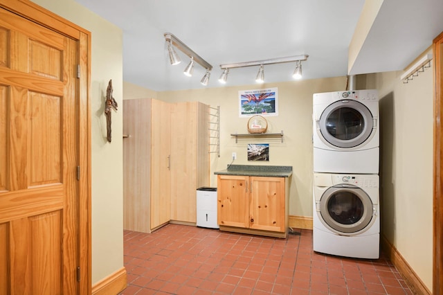 901 42nd St, Minneapolis, MN 55409 - washroom with stacked washer / drying machine, cabinet space, dark tile patterned floors, and rail lighting