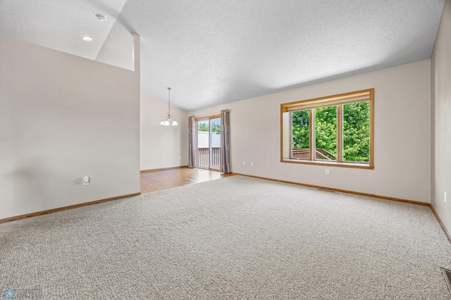 2812 Wheatland Dr S, Fargo, ND 58103 - carpeted empty room featuring a textured ceiling, lofted ceiling, a chandelier, and a smoke detector