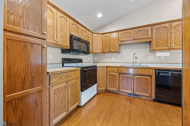 2812 Wheatland Dr S, Fargo, ND 58103 - kitchen featuring black appliances, light wood-style floors, lofted ceiling, light countertops, and brown cabinetry