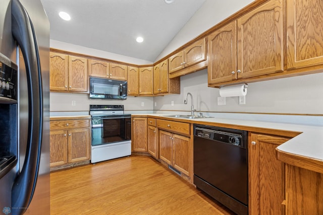 2812 Wheatland Dr S, Fargo, ND 58103 - kitchen featuring black appliances, light countertops, light wood-style floors, vaulted ceiling, and brown cabinetry