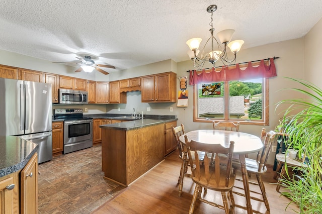 39123 Kc Dr, Homer Twp, MN 55987 - kitchen with appliances with stainless steel finishes, a peninsula, a textured ceiling, dark countertops, and brown cabinets