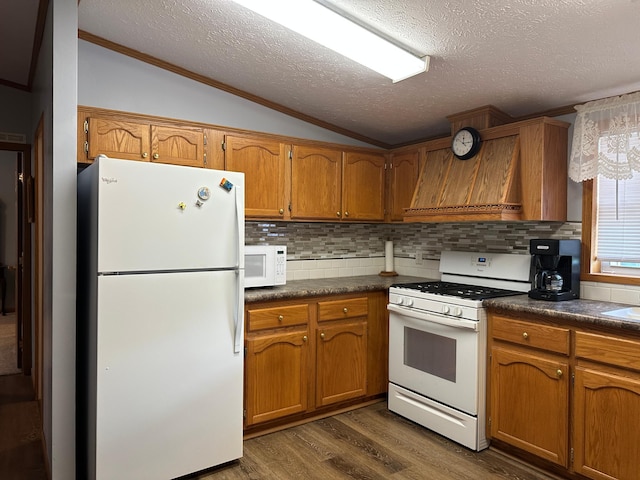 217 4th Ave SE, Pipestone, MN 56164 - kitchen with white appliances, brown cabinets, lofted ceiling, dark countertops, and ornamental molding