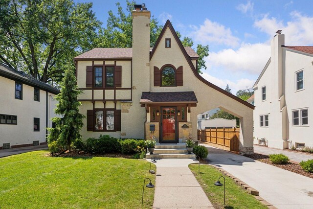 4510 Arden Ave, Edina, MN 55424 - tudor house with concrete driveway, stucco siding, roof with shingles, a chimney, and a garage