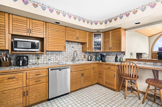 9614 Hayes Rd, Mountain Iron, MN 55768 - kitchen featuring appliances with stainless steel finishes, tile counters, decorative backsplash, glass insert cabinets, and light floors