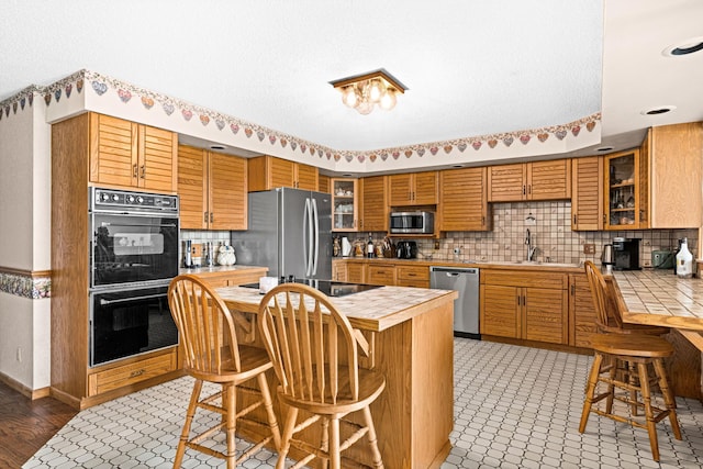 9614 Hayes Rd, Mountain Iron, MN 55768 - kitchen with black appliances, tile countertops, a breakfast bar, and tasteful backsplash