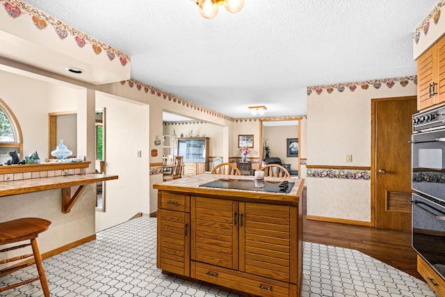 9614 Hayes Rd, Mountain Iron, MN 55768 - kitchen featuring black appliances, tile counters, a textured ceiling, and wood finished floors