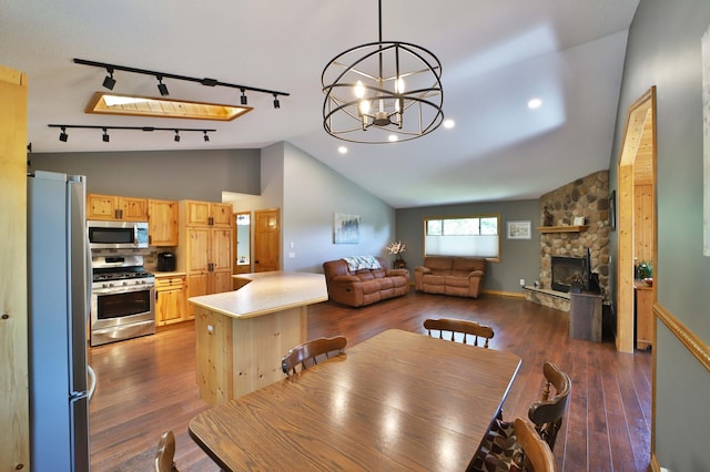 30467 Lakeview Dr, Breezy Point, MN 56472 - dining area featuring rail lighting, dark wood-style flooring, lofted ceiling, a chandelier, and a stone fireplace