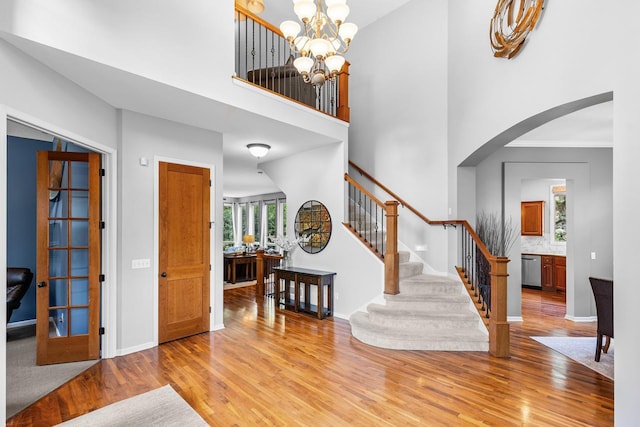 12346 Harvard Ave, Eden Prairie, MN 55347 - entryway with light wood-style floors, arched walkways, stairway, a high ceiling, and a chandelier