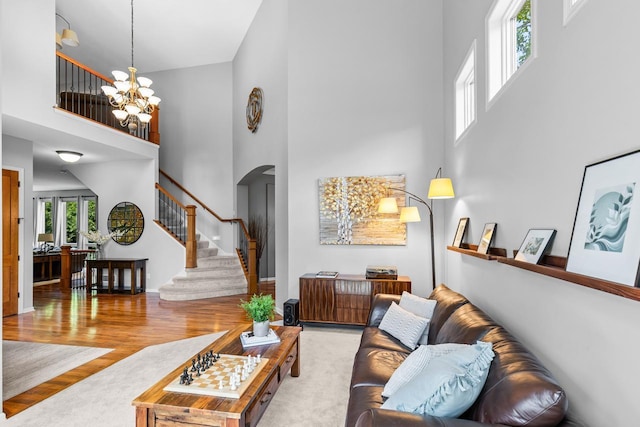 12346 Harvard Ave, Eden Prairie, MN 55347 - living room featuring a towering ceiling, arched walkways, a chandelier, wood finished floors, and stairs