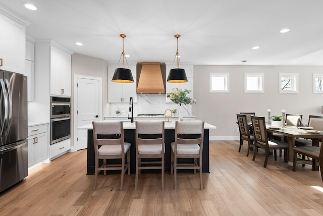 7617 Ocean Ave NE, Otsego, MN 55330 - kitchen featuring premium range hood, appliances with stainless steel finishes, light wood-style floors, backsplash, and recessed lighting