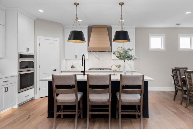 7617 Ocean Ave NE, Otsego, MN 55330 - kitchen with custom exhaust hood, double oven, backsplash, light wood-style floors, and light countertops