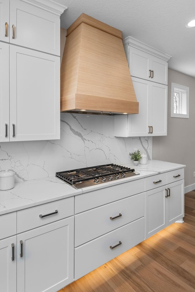 7617 Ocean Ave NE, Otsego, MN 55330 - kitchen with custom exhaust hood, stainless steel gas stovetop, backsplash, white cabinetry, and recessed lighting