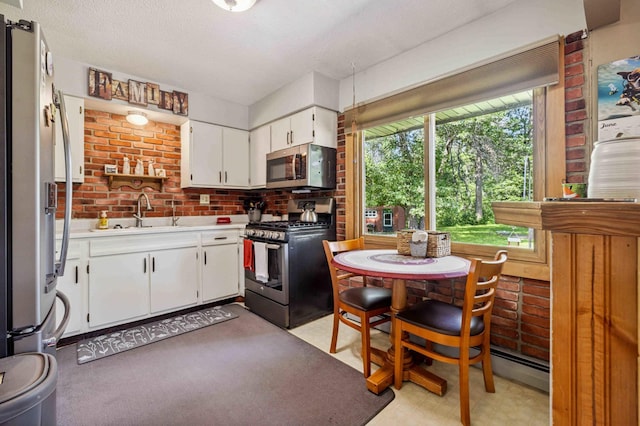 4745 Patterson Trl, Brainerd, MN 56401 - kitchen with appliances with stainless steel finishes, light countertops, white cabinets, baseboard heating, and brick wall