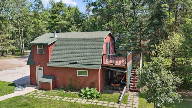 4745 Patterson Trl, Brainerd, MN 56401 - view of home's exterior featuring stairway, a gambrel roof, a wooden deck, a lawn, and a shingled roof