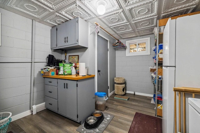 4745 Patterson Trl, Brainerd, MN 56401 - kitchen featuring freestanding refrigerator, gray cabinetry, concrete block wall, dark wood-type flooring, and an ornate ceiling