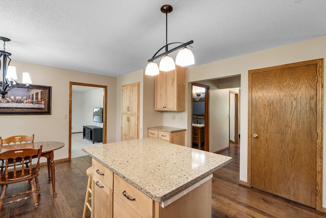 621 Twelve Oaks Ln, Hudson, WI 54016 - kitchen with light brown cabinetry, a chandelier, dark wood-style floors, a kitchen island, and a textured ceiling