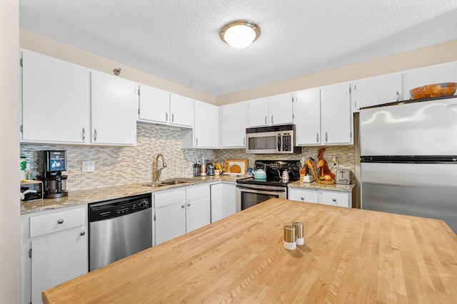 121 Washington Ave S Unit 513, Minneapolis, MN 55401 - kitchen with appliances with stainless steel finishes, decorative backsplash, white cabinets, a textured ceiling, and wooden counters