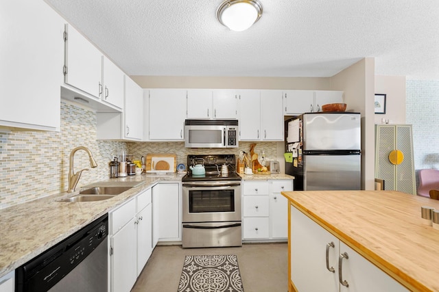 121 Washington Ave S Unit 513, Minneapolis, MN 55401 - kitchen featuring appliances with stainless steel finishes, a textured ceiling, tasteful backsplash, white cabinetry, and butcher block counters