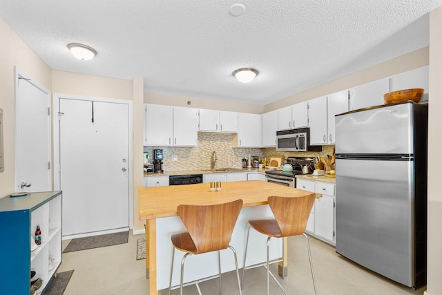 121 Washington Ave S Unit 513, Minneapolis, MN 55401 - kitchen with stainless steel appliances, tasteful backsplash, a breakfast bar, white cabinets, and a textured ceiling