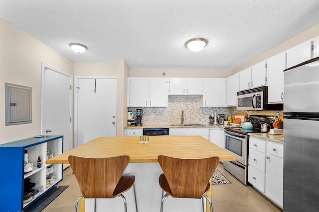 121 Washington Ave S Unit 513, Minneapolis, MN 55401 - kitchen featuring appliances with stainless steel finishes, electric panel, decorative backsplash, white cabinetry, and finished concrete flooring