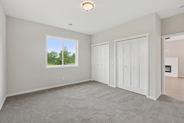 2728 229th Ln NW, Saint Francis, MN 55070 - unfurnished bedroom with multiple closets, carpet, and a glass covered fireplace