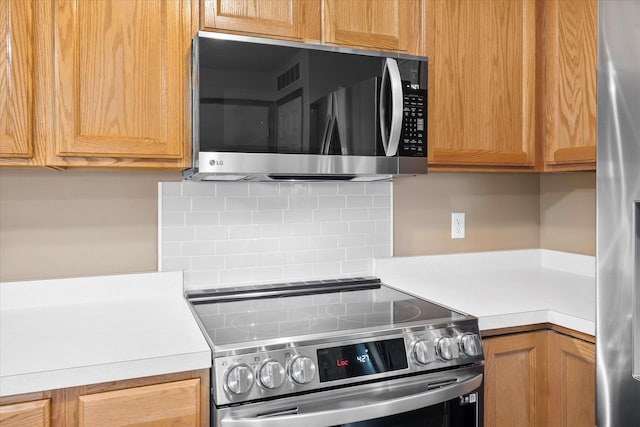 8731 Quarry Ridge Ln Unit B, Woodbury, MN 55125 - kitchen with stainless steel appliances, decorative backsplash, and light countertops