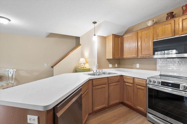 8731 Quarry Ridge Ln Unit B, Woodbury, MN 55125 - kitchen featuring appliances with stainless steel finishes, light wood-style flooring, light countertops, a peninsula, and brown cabinetry
