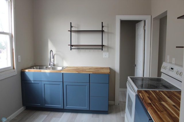 921 6th Ave N, Fargo, ND 58102 - kitchen with wooden counters, white range with electric cooktop, open shelves, light wood-type flooring, and blue cabinetry