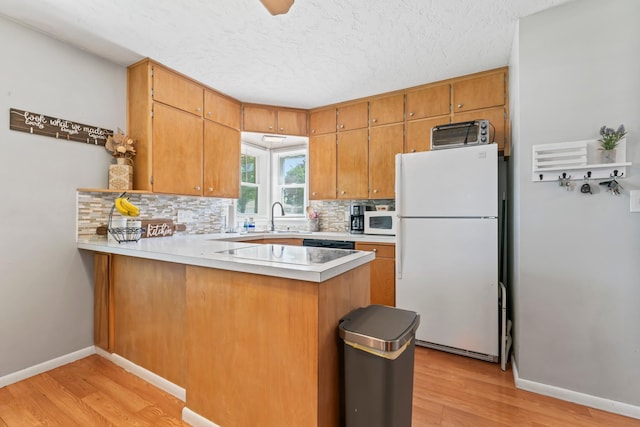 1917 2nd Ave NW, Austin, MN 55912 - kitchen featuring white appliances, light wood-style floors, backsplash, a peninsula, and light countertops