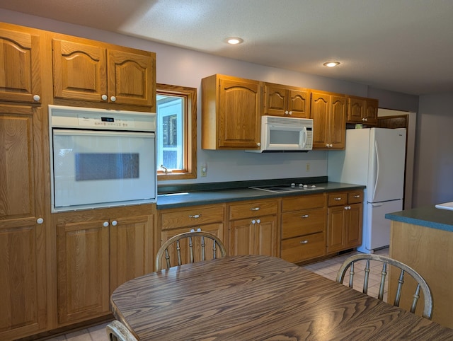 417 Ridge Rd, Albert Lea, MN 56007 - kitchen with white appliances, dark countertops, brown cabinetry, and recessed lighting