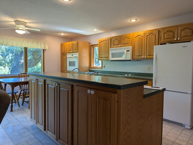 417 Ridge Rd, Albert Lea, MN 56007 - kitchen featuring white appliances, dark countertops, ceiling fan, plenty of natural light, and a textured ceiling
