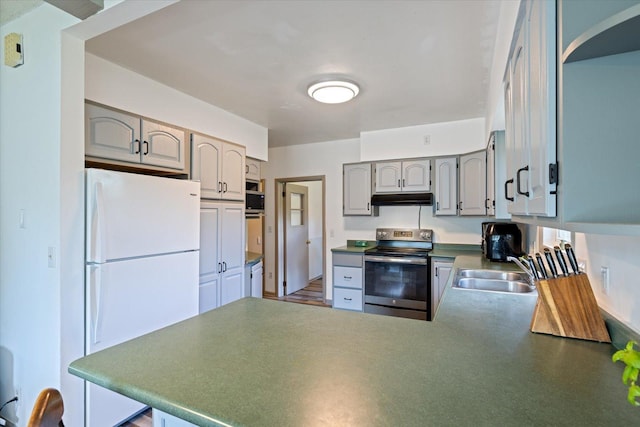 602 8th St NW, Chisholm, MN 55719 - kitchen with stainless steel electric range, freestanding refrigerator, under cabinet range hood, a peninsula, and gray cabinets