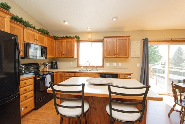 2223 Fairbanks Dr, North Mankato, MN 56003 - kitchen featuring black appliances, a breakfast bar, light countertops, a kitchen island, and brown cabinetry