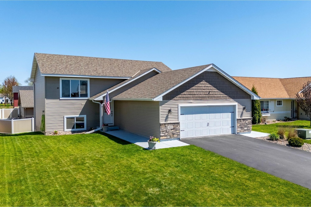 462 Marcella Ln, Somerset, WI 54025 - view of front of home featuring a garage, a front yard, asphalt driveway, stone siding, and a shingled roof