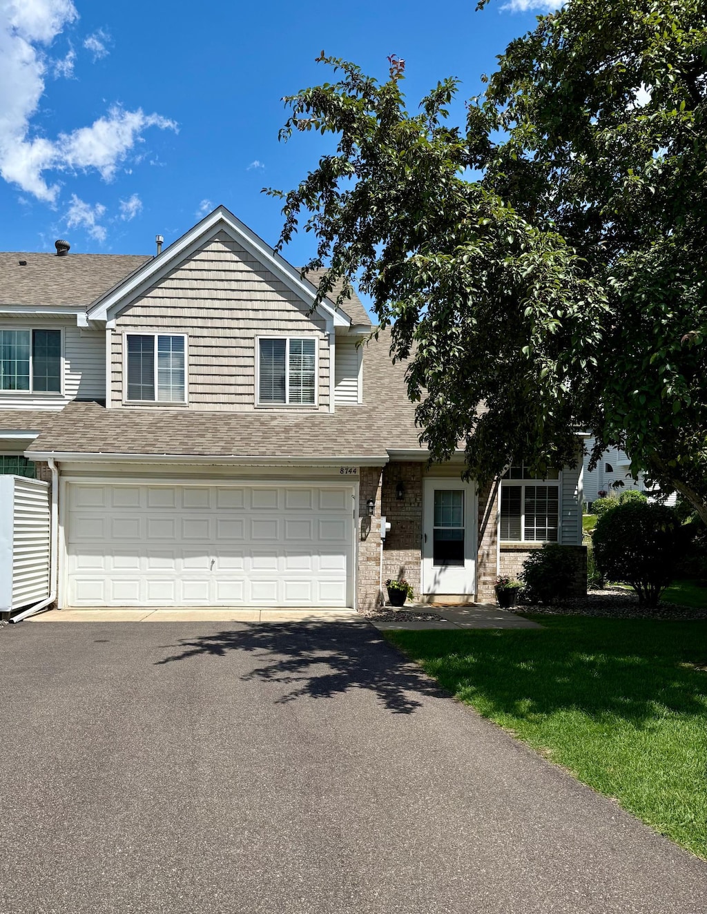 8744 Bechtel Ave Unit 109, Inver Grove Heights, MN 55076 - traditional-style home featuring driveway, an attached garage, a shingled roof, and a front lawn