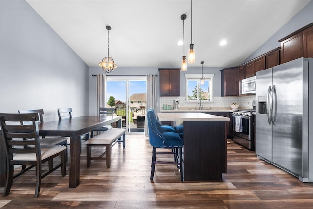 8638 Preserve Blvd N, Chisago City, MN 55013 - kitchen featuring appliances with stainless steel finishes, vaulted ceiling, light countertops, dark brown cabinetry, and backsplash