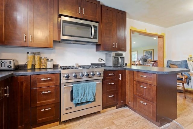 322 Central Ave N, Eagle Bend, MN 56446 - kitchen featuring stainless steel appliances, dark countertops, light wood-style flooring, and a peninsula