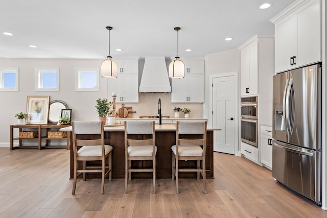 3886 Larabee Ave NE, Saint Michael, MN 55376 - kitchen featuring stainless steel appliances, premium range hood, light countertops, a breakfast bar area, and an island with sink