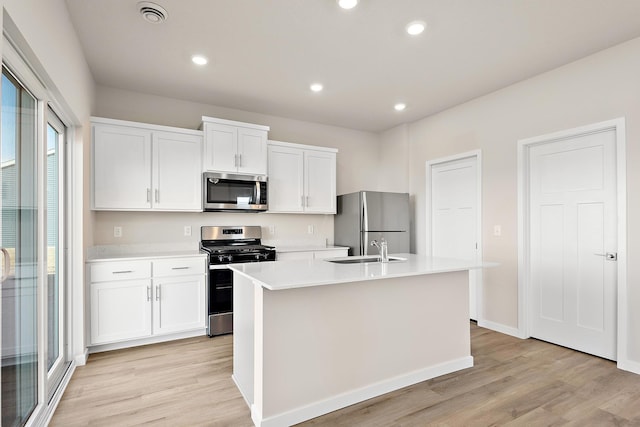 39749 Fallbrook Ave, North Branch, MN 55056 - kitchen with stainless steel appliances, light countertops, light wood-style flooring, a center island with sink, and white cabinets