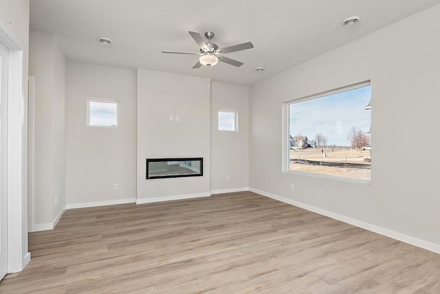 39749 Fallbrook Ave, North Branch, MN 55056 - unfurnished living room featuring wood finished floors, a glass covered fireplace, and ceiling fan