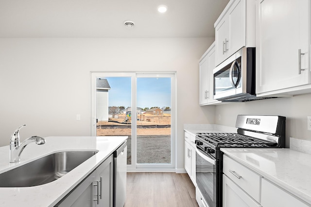39749 Fallbrook Ave, North Branch, MN 55056 - kitchen with stainless steel appliances, light wood-style floors, light stone counters, white cabinetry, and recessed lighting
