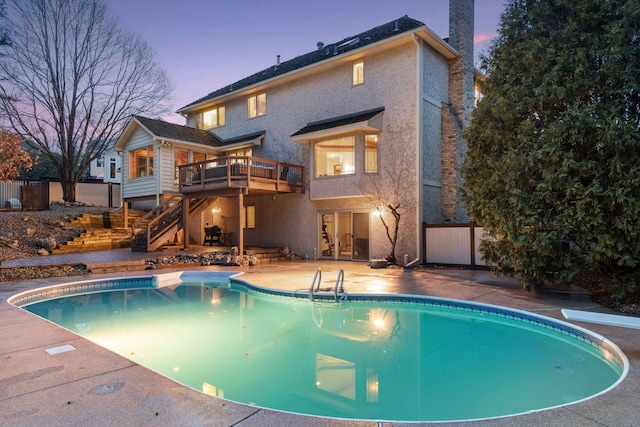 3600 Wedgewood Ln N, Plymouth, MN 55441 - back of house at dusk with stucco siding, stairway, an outdoor pool, and a wooden deck