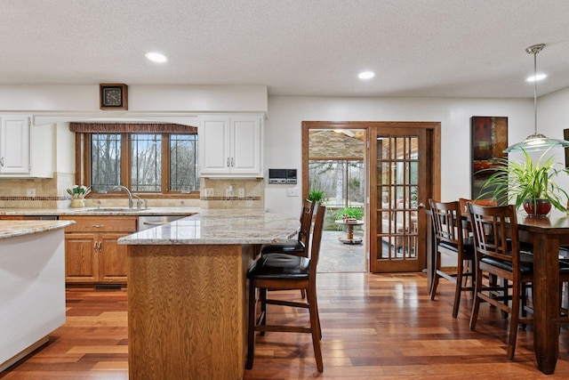 3600 Wedgewood Ln N, Plymouth, MN 55441 - kitchen featuring light wood finished floors, a breakfast bar area, decorative backsplash, light stone countertops, and recessed lighting
