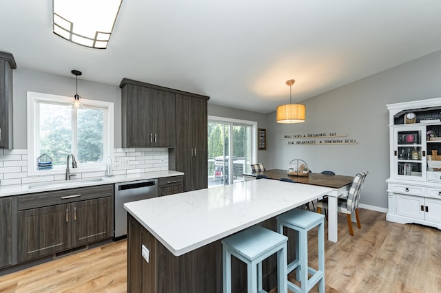 2 Lillie Ln SE, Pine Island, MN 55963 - kitchen with stainless steel dishwasher, dark brown cabinetry, decorative backsplash, light wood-style floors, and a breakfast bar